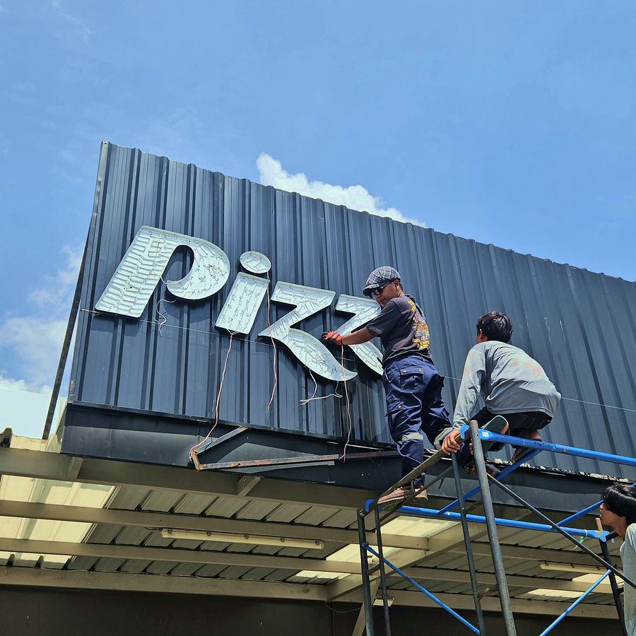 ทีมงานติดตั้งตัวอักษรป้าย Pizza Hut บน facade